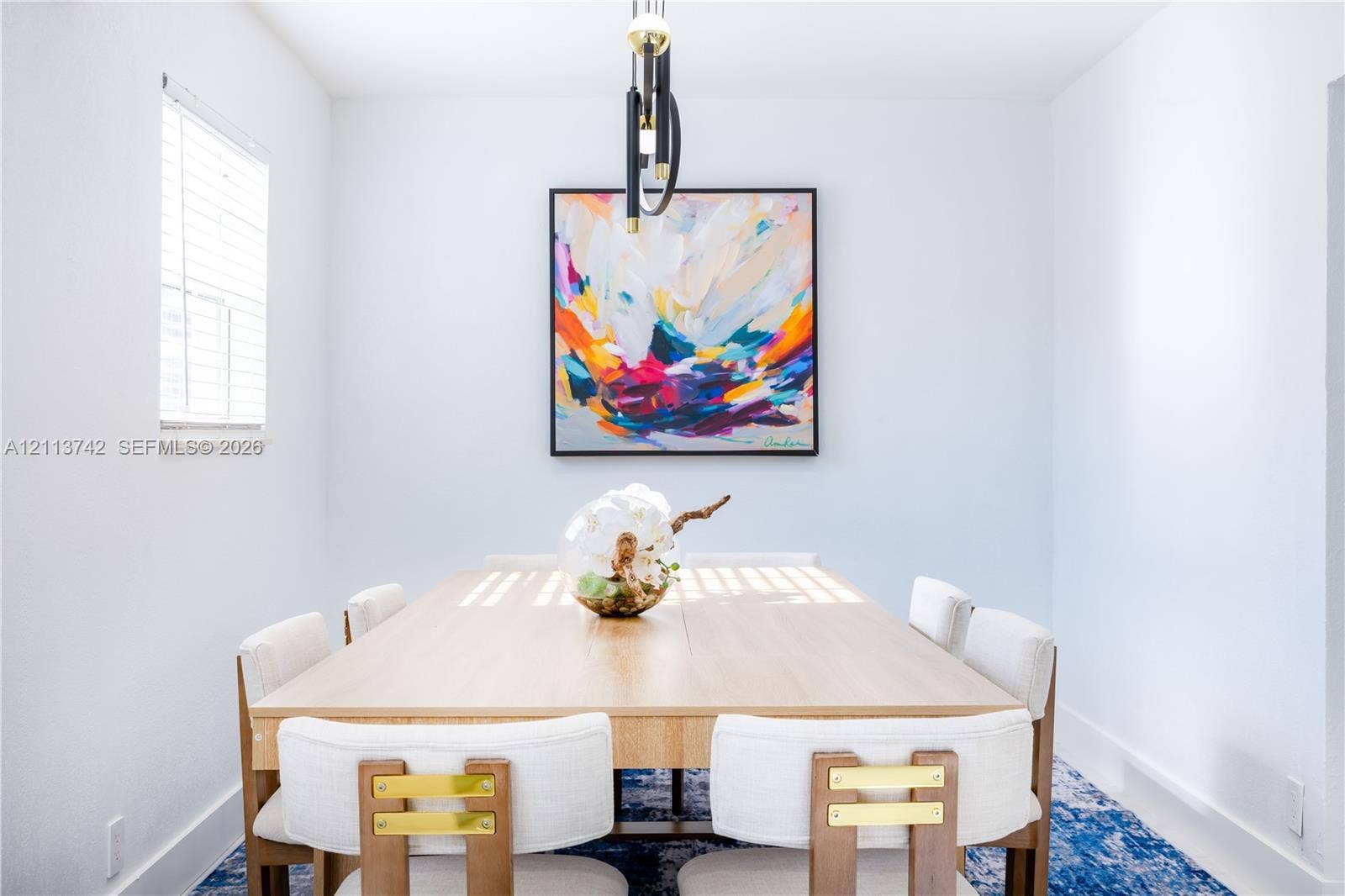 1930 NW 163rd St Road, Miami Gardens, FL 33054 Dining area featuring neutral wall paint, modern multi-tiered linear pendant lighting, and a single window with horizontal blinds