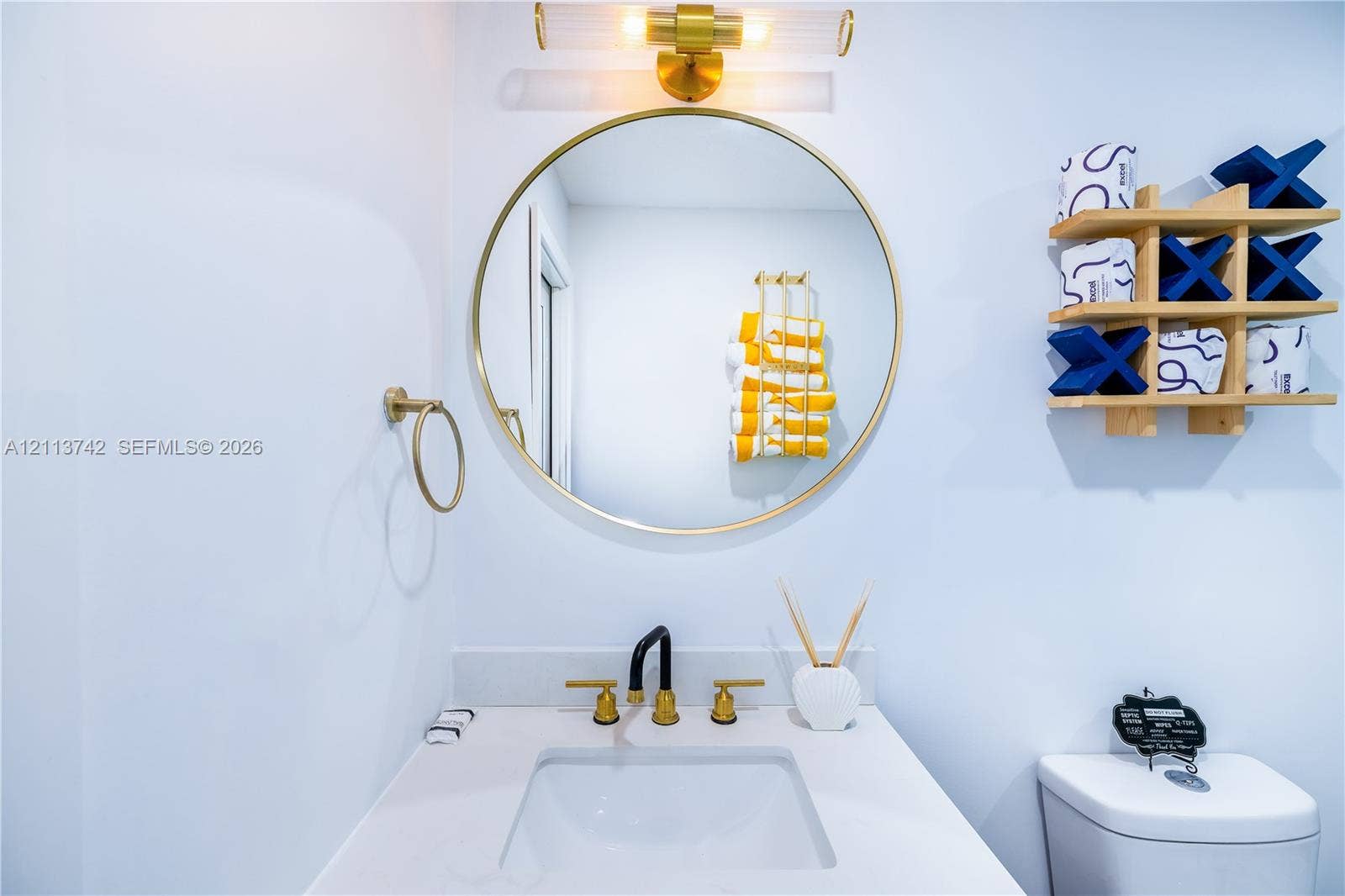 1930 NW 163rd St Road, Miami Gardens, FL 33054 Bathroom vanity featuring a quartz countertop, rectangular undermount sink, brass finish widespread faucet, round brass-framed mirror, and a linear wall-mounted light fixture