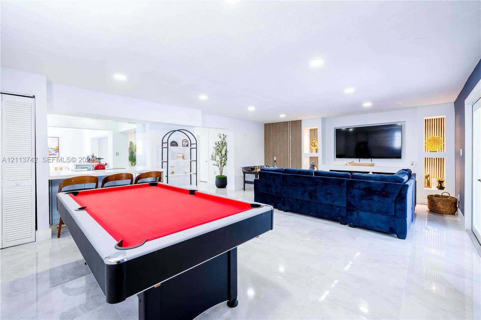 1930 NW 163rd St Road, Miami Gardens, FL 33054 Large open-concept space featuring polished tile flooring, recessed ceiling lighting, a built-in media wall with integrated shelving, and a bar area with custom cabinetry