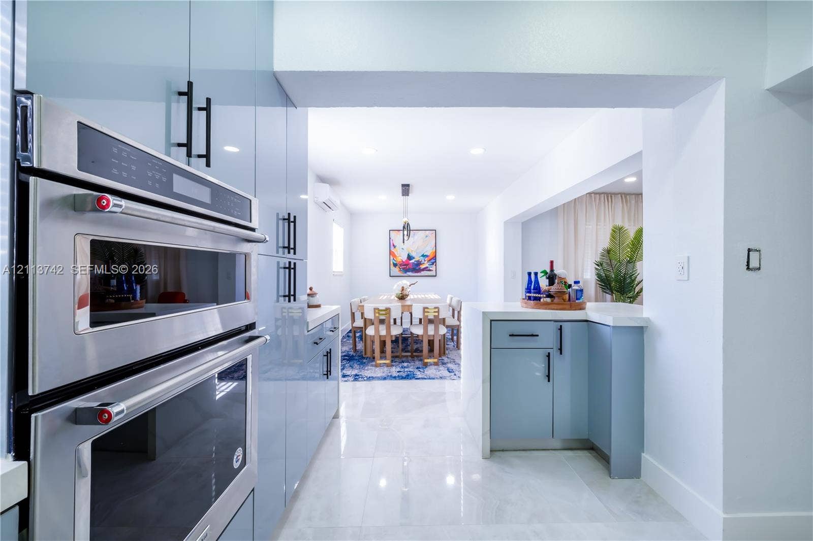 1930 NW 163rd St Road, Miami Gardens, FL 33054 Kitchen featuring high-gloss blue cabinetry, built-in stainless steel wall oven, recessed ceiling lighting, and tile flooring