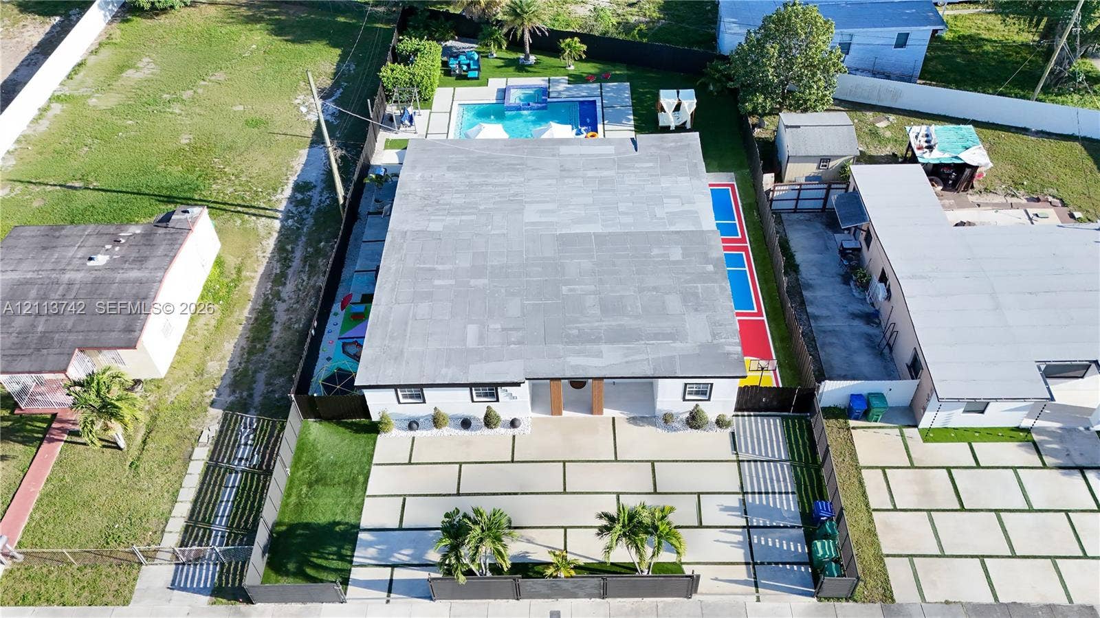 1930 NW 163rd St Road, Miami Gardens, FL 33054 Aerial perspective featuring a structured concrete driveway with integrated turf ribbons, a rear swimming pool with integrated spa, and a multi-purpose sport court