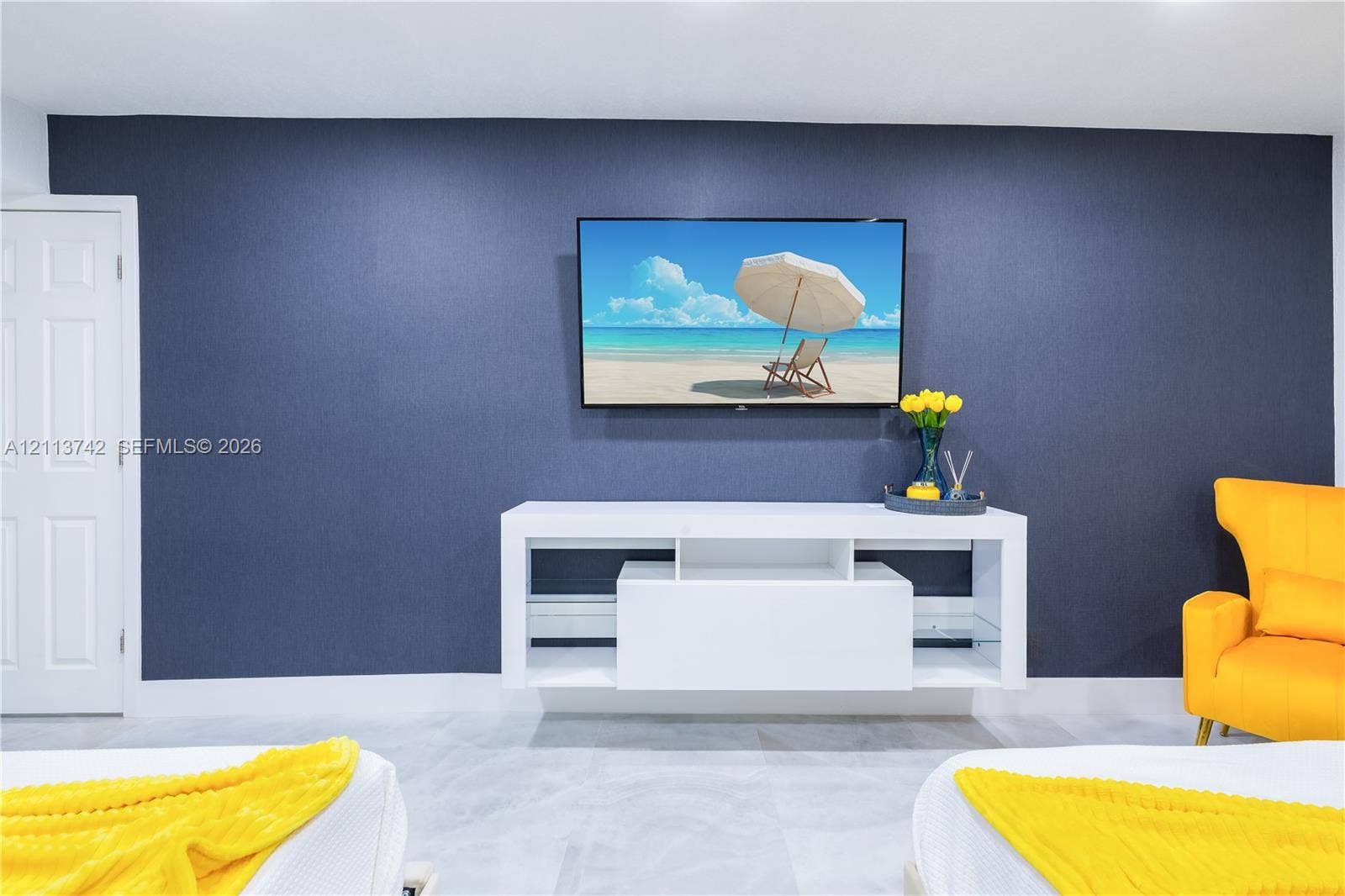 1930 NW 163rd St Road, Miami Gardens, FL 33054 Deep blue accent wall with a wall-mounted television, white built-in media console, and large-format tile flooring