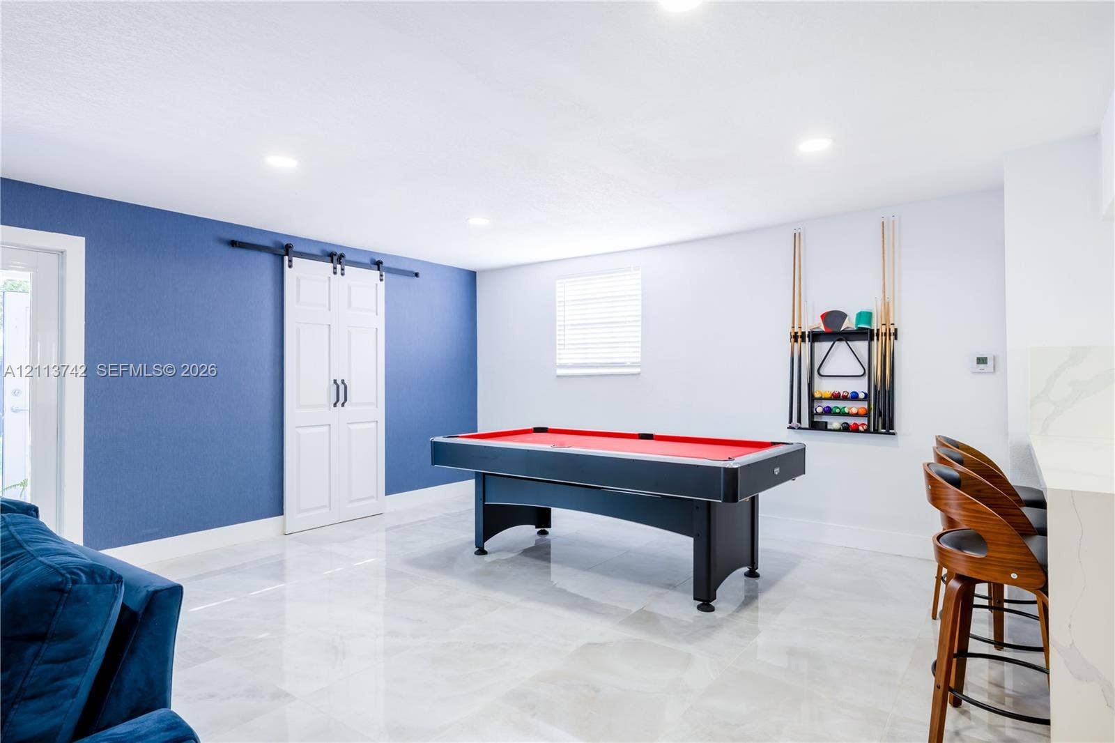 1930 NW 163rd St Road, Miami Gardens, FL 33054 Recessed lighting, large-format tile flooring, blue accent wall, white sliding barn door, and a built-in stone-top bar surface