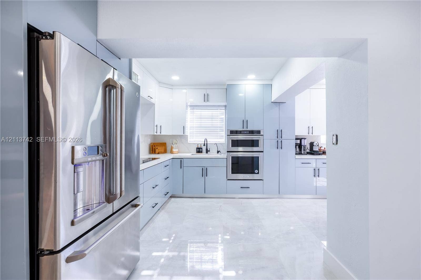 1930 NW 163rd St Road, Miami Gardens, FL 33054 Kitchen featuring light blue custom cabinetry, stainless steel appliances including a built-in double oven and French door refrigerator, white countertops, and polished tile flooring