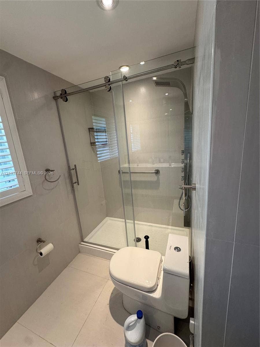 1501 Arthur Street, #1, Hollywood, FL 33020 Walk-in shower featuring a sliding glass door, rainfall showerhead, integrated grab bar, and large-format wall tile
