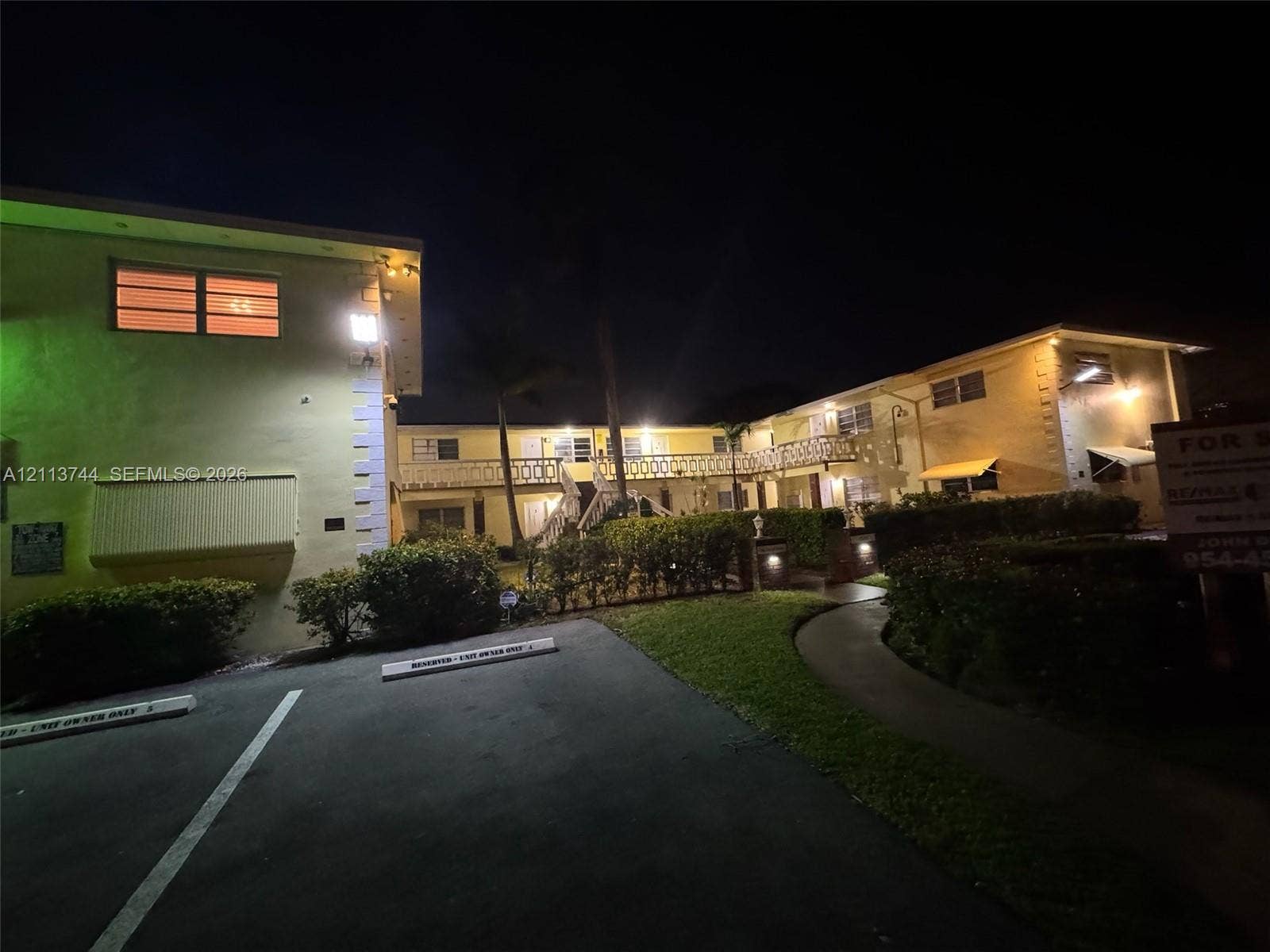 1501 Arthur Street, #1, Hollywood, FL 33020 Multi-story exterior featuring masonry construction, a concrete walkway, designated parking spaces, and decorative railing