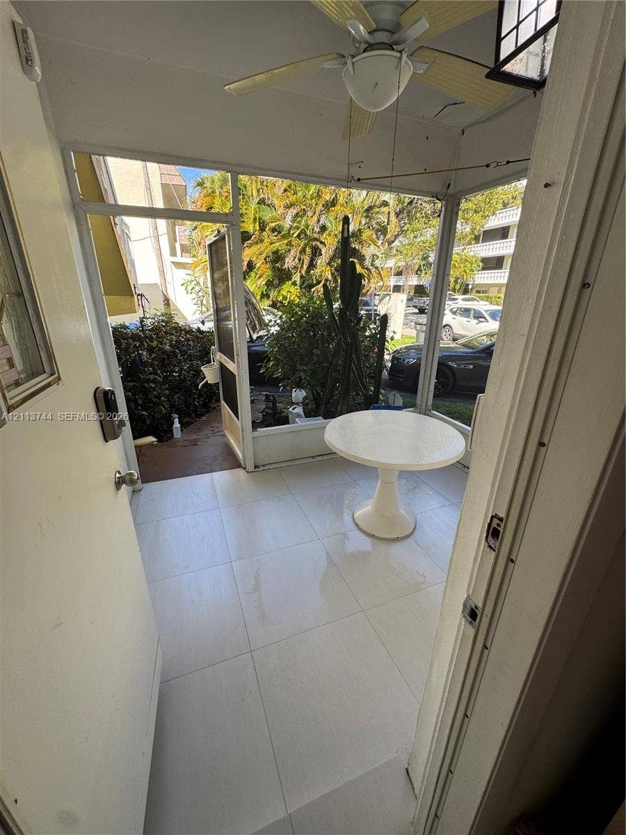 1501 Arthur Street, #1, Hollywood, FL 33020 Screened-in porch featuring large-format tile flooring, a mounted ceiling fan, and a swinging screen door