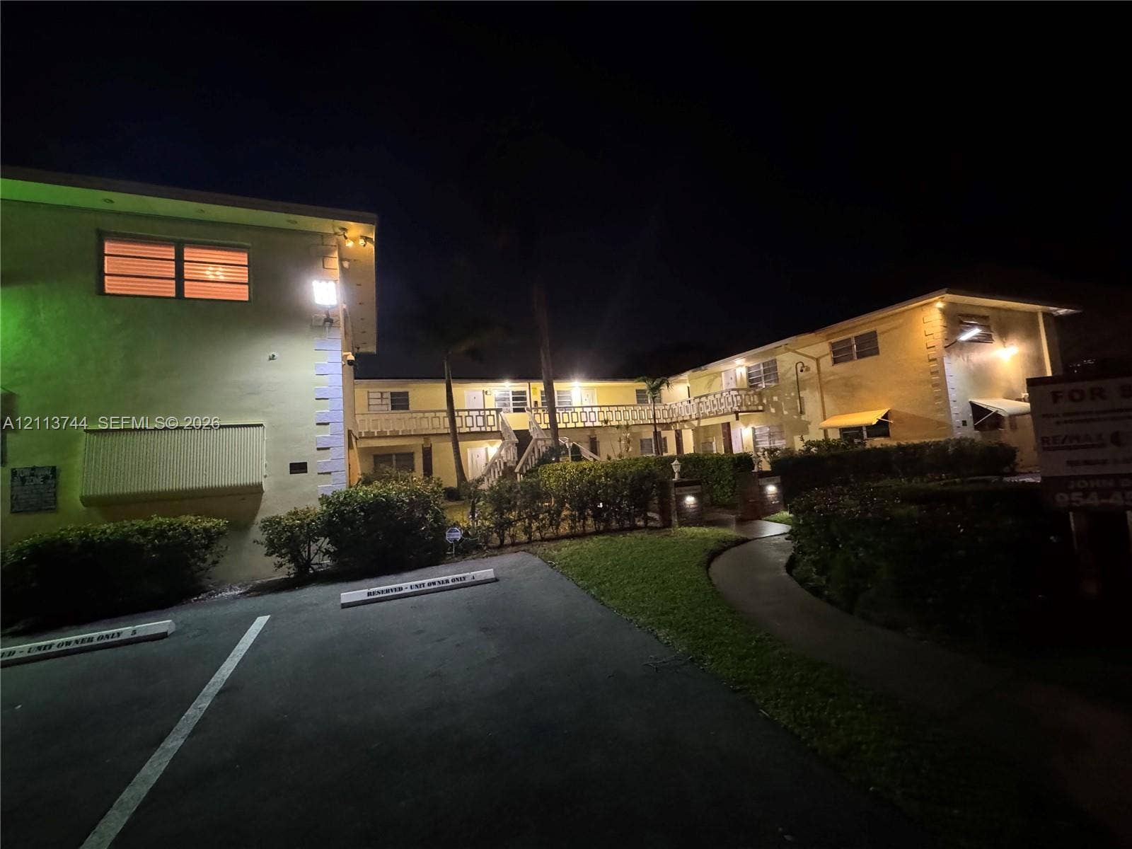 1501 Arthur Street, #1, Hollywood, FL 33020 Two-story exterior featuring a stucco facade, decorative geometric railings, covered walkways, and paved parking area with designated spaces