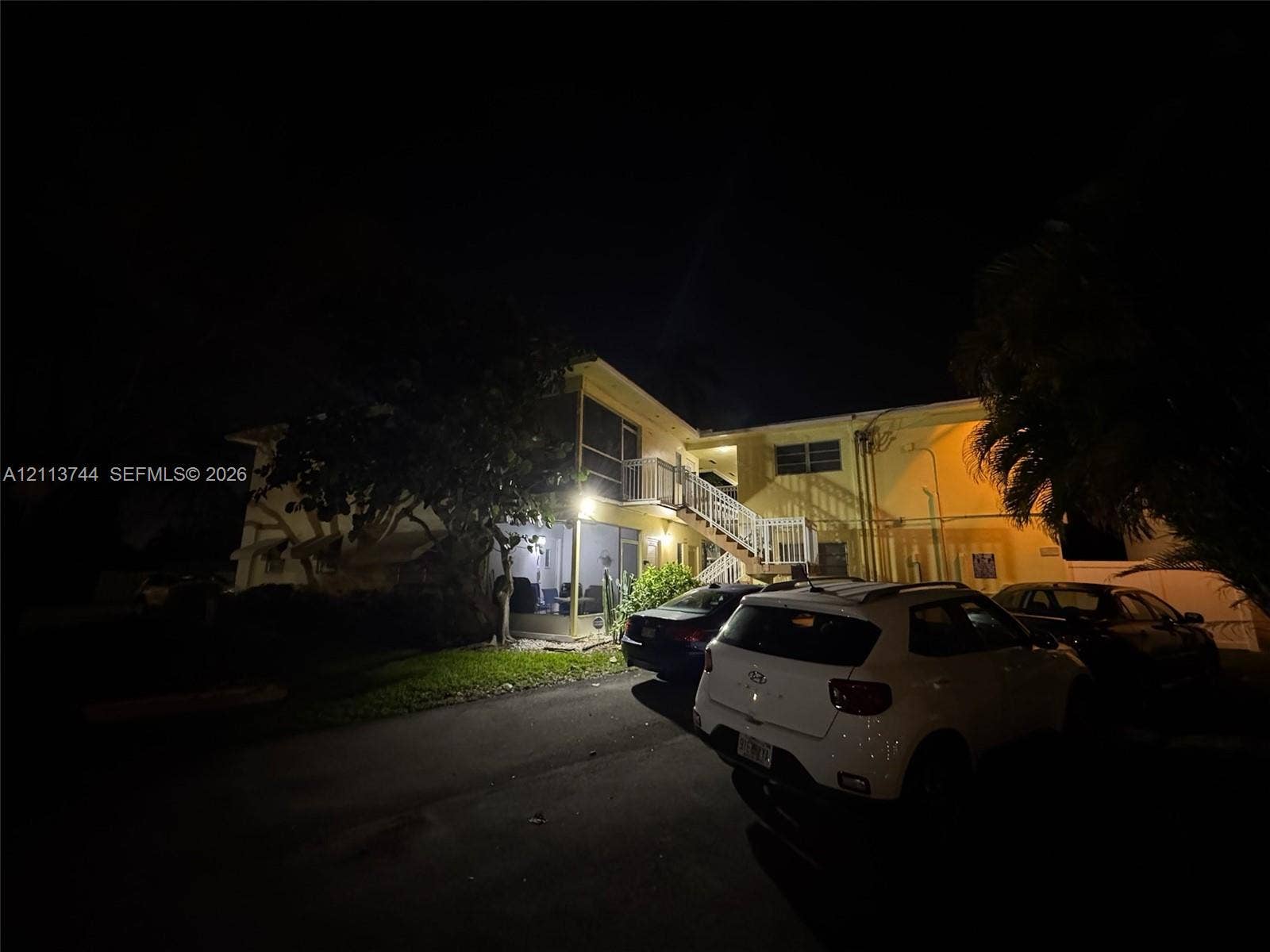 1501 Arthur Street, #1, Hollywood, FL 33020 Two-story exterior featuring a screened balcony, metal staircase, and paved off-street parking