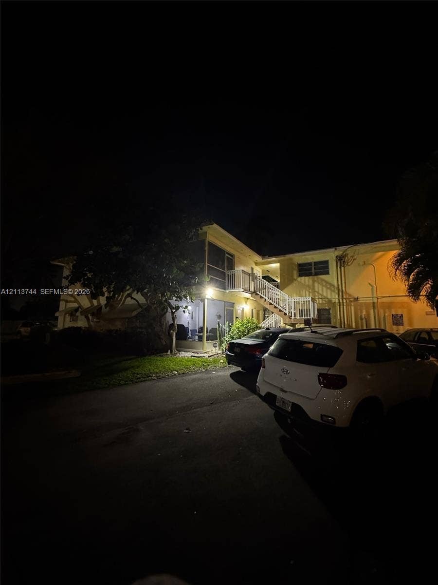 1501 Arthur Street, #1, Hollywood, FL 33020 Two-story exterior featuring a screened-in lanai, concrete staircase with metal railing, and paved parking area