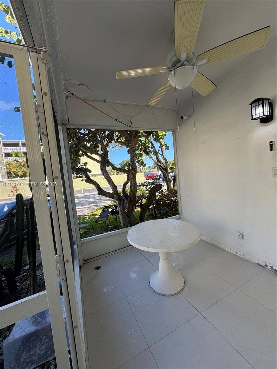 1501 Arthur Street, #1, Hollywood, FL 33020 Screened-in porch featuring large-format tile flooring, a ceiling fan with integrated lighting, and a wall-mounted lantern-style exterior fixture