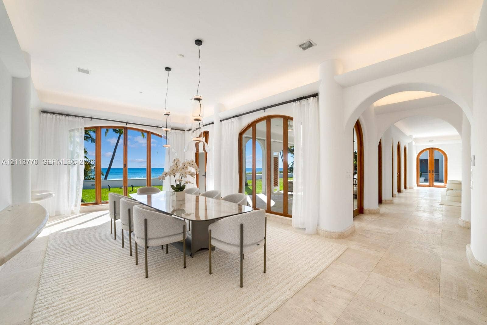 387 Ocean Boulevard, Golden Beach, Golden Beach, FL 33160 Open-concept area featuring stone flooring, arched architectural detailing, dual sets of arched wood-framed glass doors, and recessed cove lighting