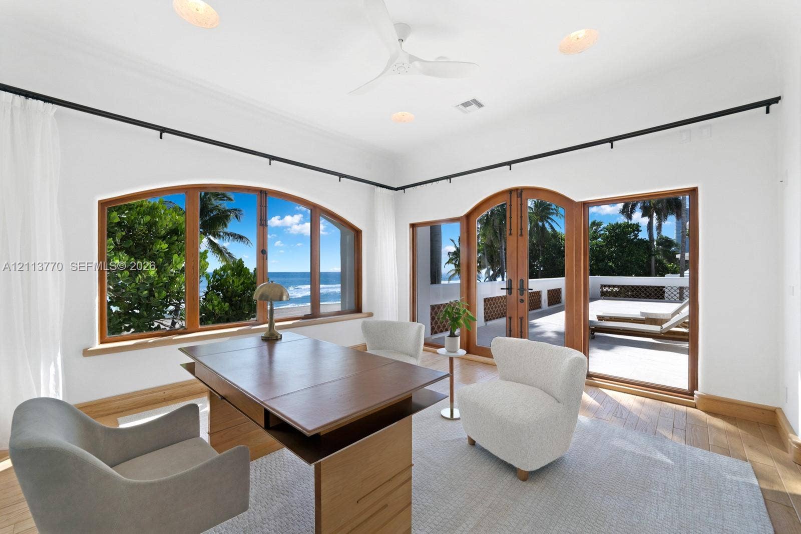387 Ocean Boulevard, Golden Beach, Golden Beach, FL 33160 Arched wood-framed windows, double wood-framed glass doors, wood-finish flooring, recessed lighting, and a ceiling fan