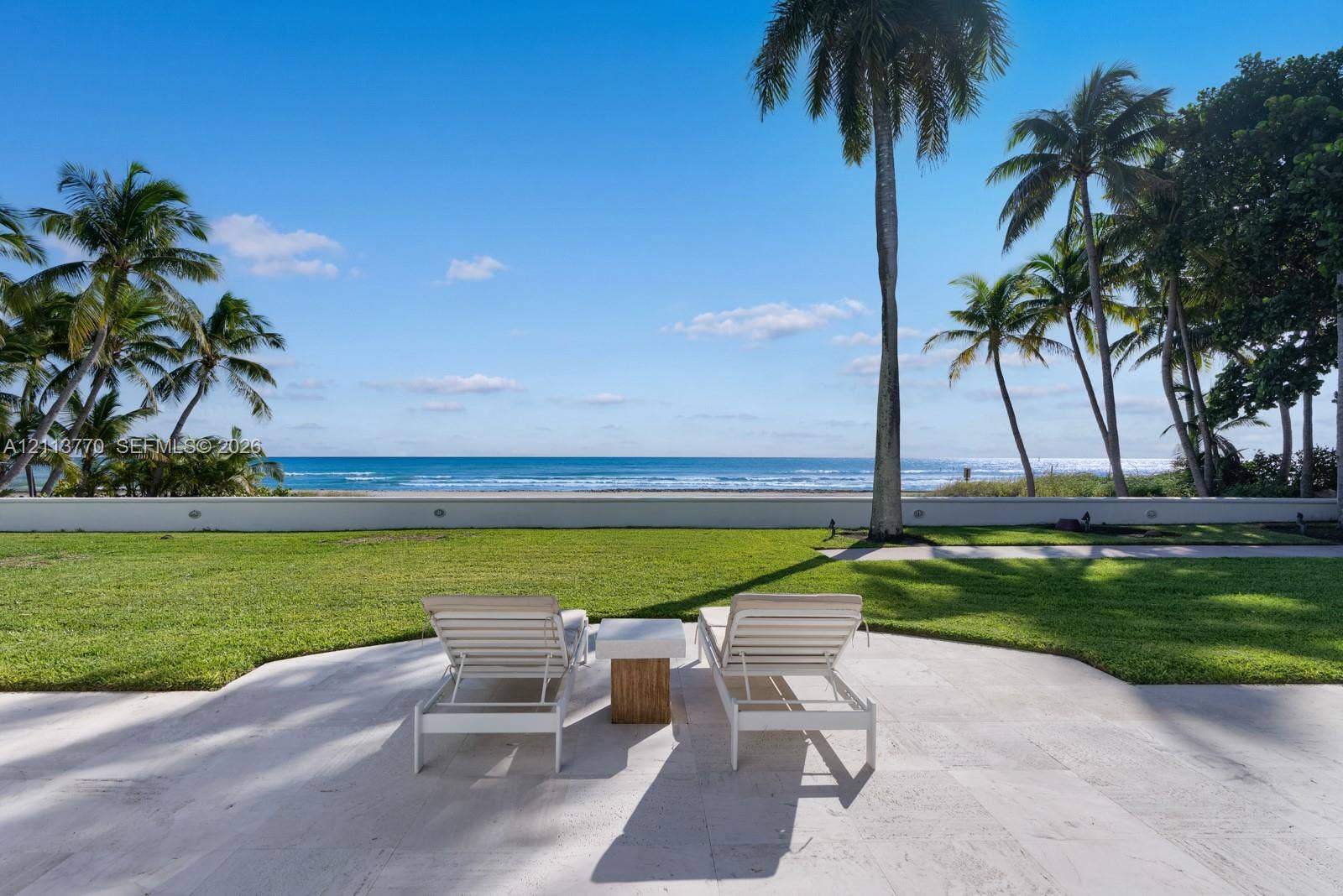 387 Ocean Boulevard, Golden Beach, Golden Beach, FL 33160 Stone-paved patio featuring a manicured lawn, perimeter masonry wall, and oceanfront exposure