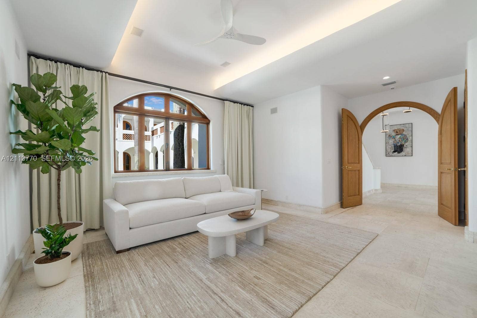 387 Ocean Boulevard, Golden Beach, Golden Beach, FL 33160 Tray ceiling with integrated recessed lighting, arched wood-framed window, natural stone tile flooring, and double wood-paneled arched doorway