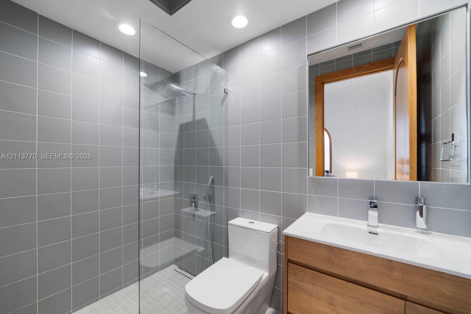 387 Ocean Boulevard, Golden Beach, Golden Beach, FL 33160 Walk-in shower with a glass panel and rainfall showerhead, vanity with a white countertop and integrated sink, and floor-to-ceiling gray wall tiling