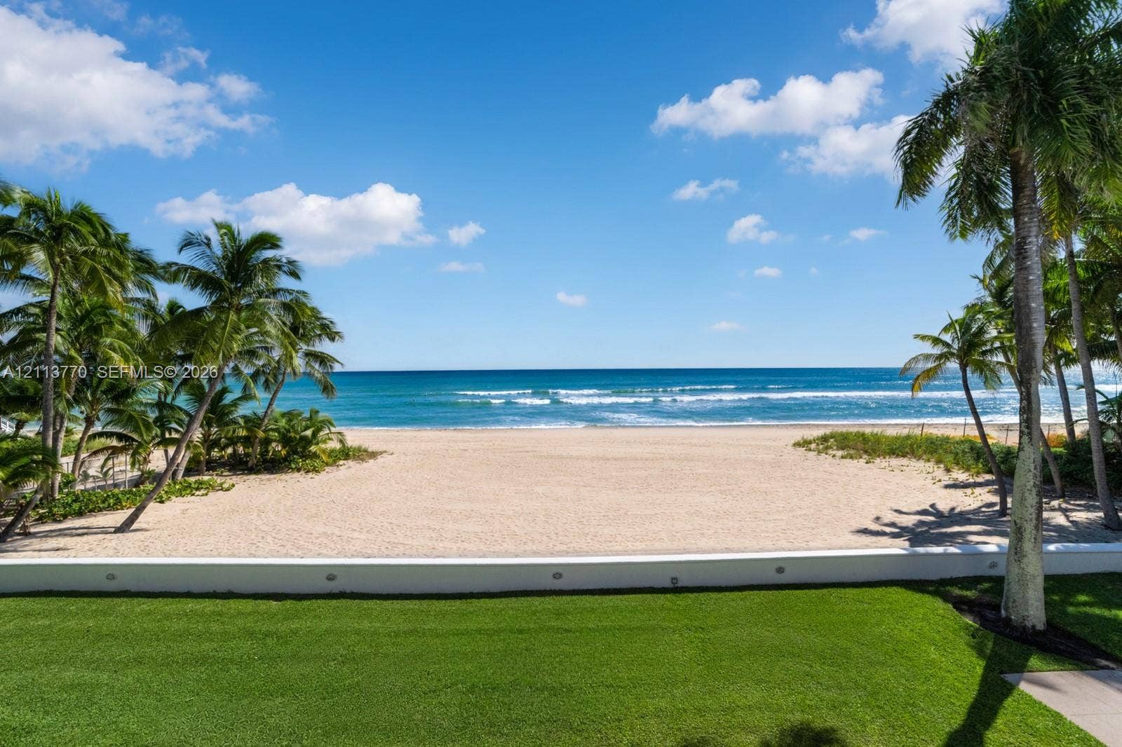 387 Ocean Boulevard, Golden Beach, Golden Beach, FL 33160 Direct beach access, manicured lawn, low-profile concrete retaining wall with integrated lighting, and mature palm trees