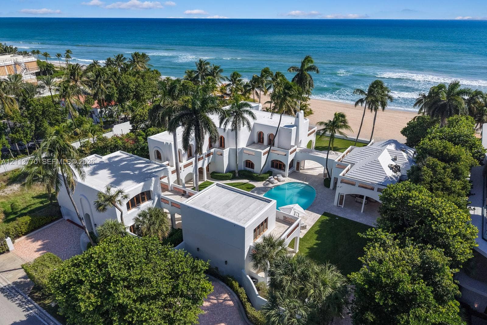 387 Ocean Boulevard, Golden Beach, Golden Beach, FL 33160 Coastal estate featuring a white stucco exterior, swimming pool, manicured lawn, stone-paved patio, and direct beach access