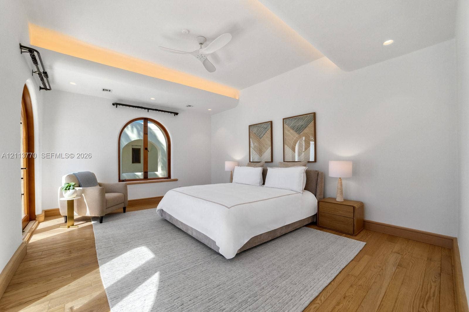 387 Ocean Boulevard, Golden Beach, Golden Beach, FL 33160 Room featuring wood-finish flooring, tray ceiling with recessed accent lighting, ceiling fan, and arched window and door frames with wood casing