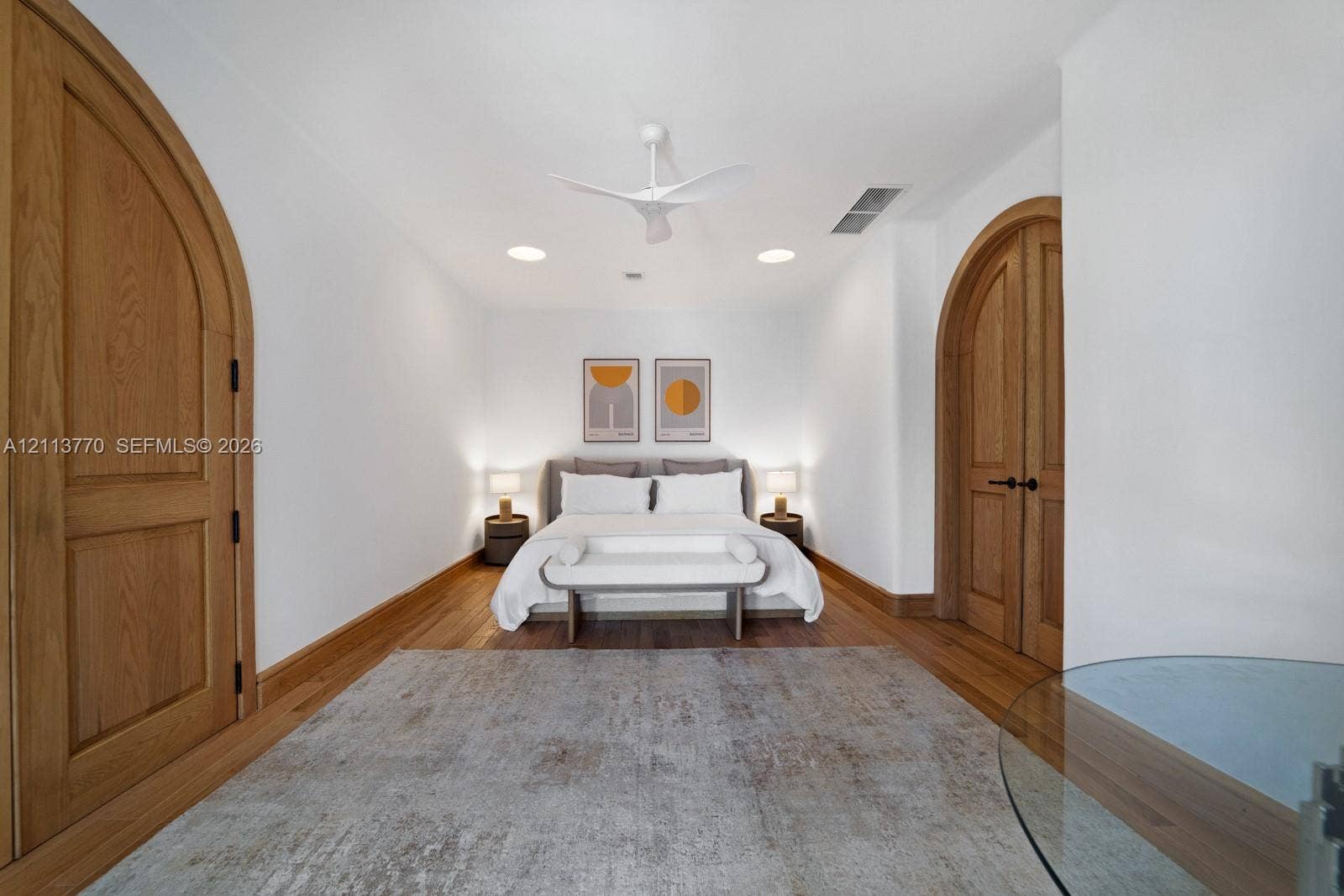 387 Ocean Boulevard, Golden Beach, Golden Beach, FL 33160 Interior room featuring arched solid wood doors, wood-finish flooring, and a modern white ceiling fan