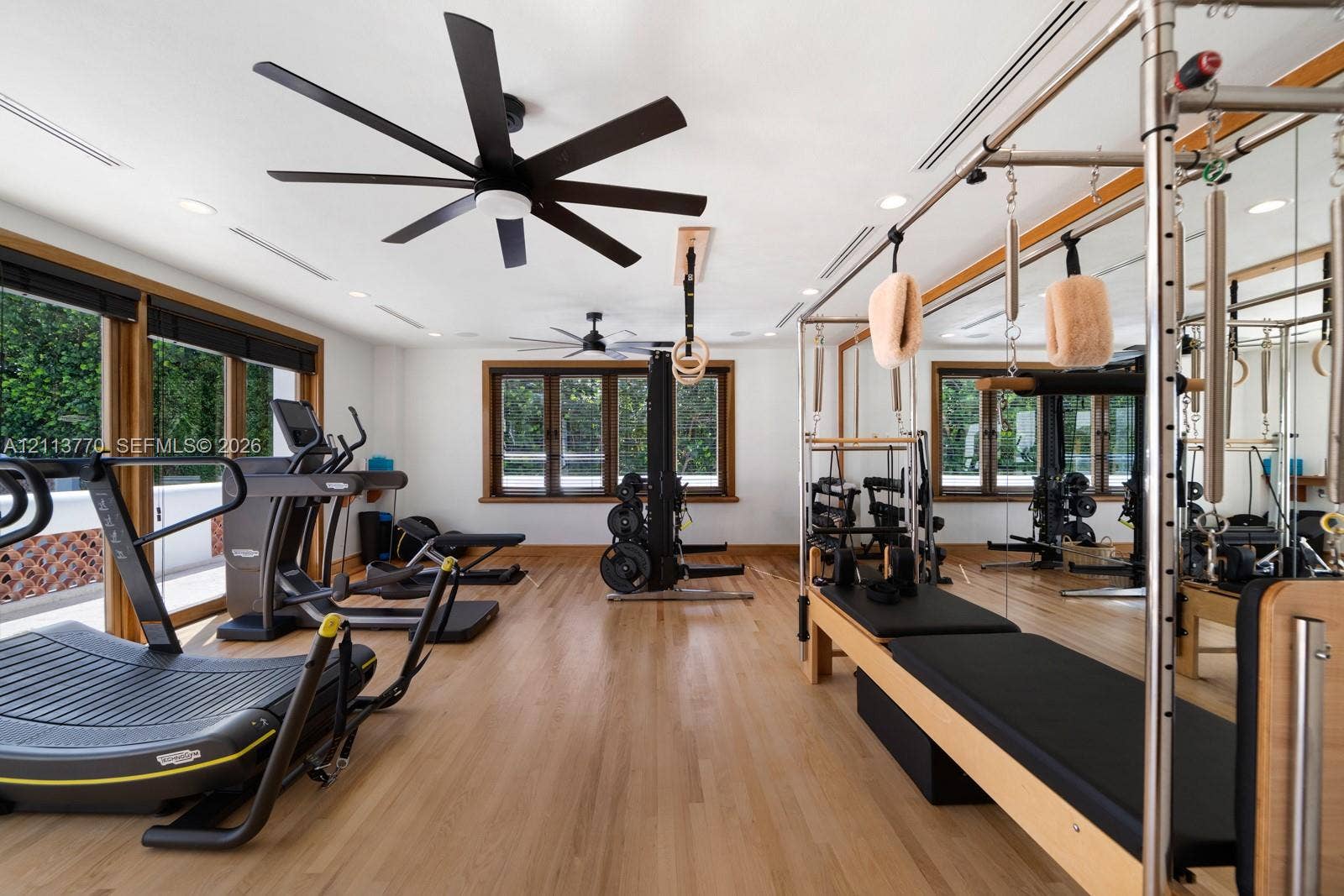 387 Ocean Boulevard, Golden Beach, Golden Beach, FL 33160 Fitness space featuring wood-finish flooring, multi-blade ceiling fans, recessed lighting, expansive wall-to-wall mirrors, and wood-trimmed windows