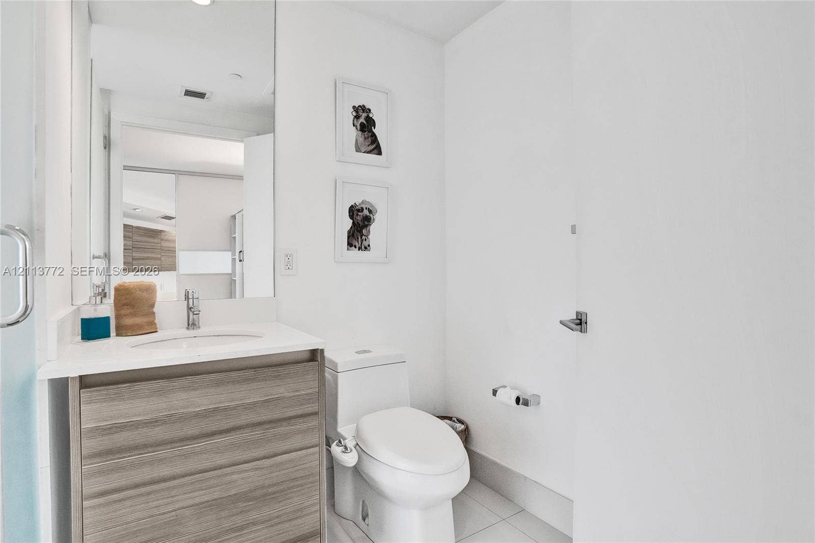 Bathroom featuring a floating wood-finish vanity, integrated white countertop with a recessed basin, chrome single-lever faucet, and large-format wall mirror