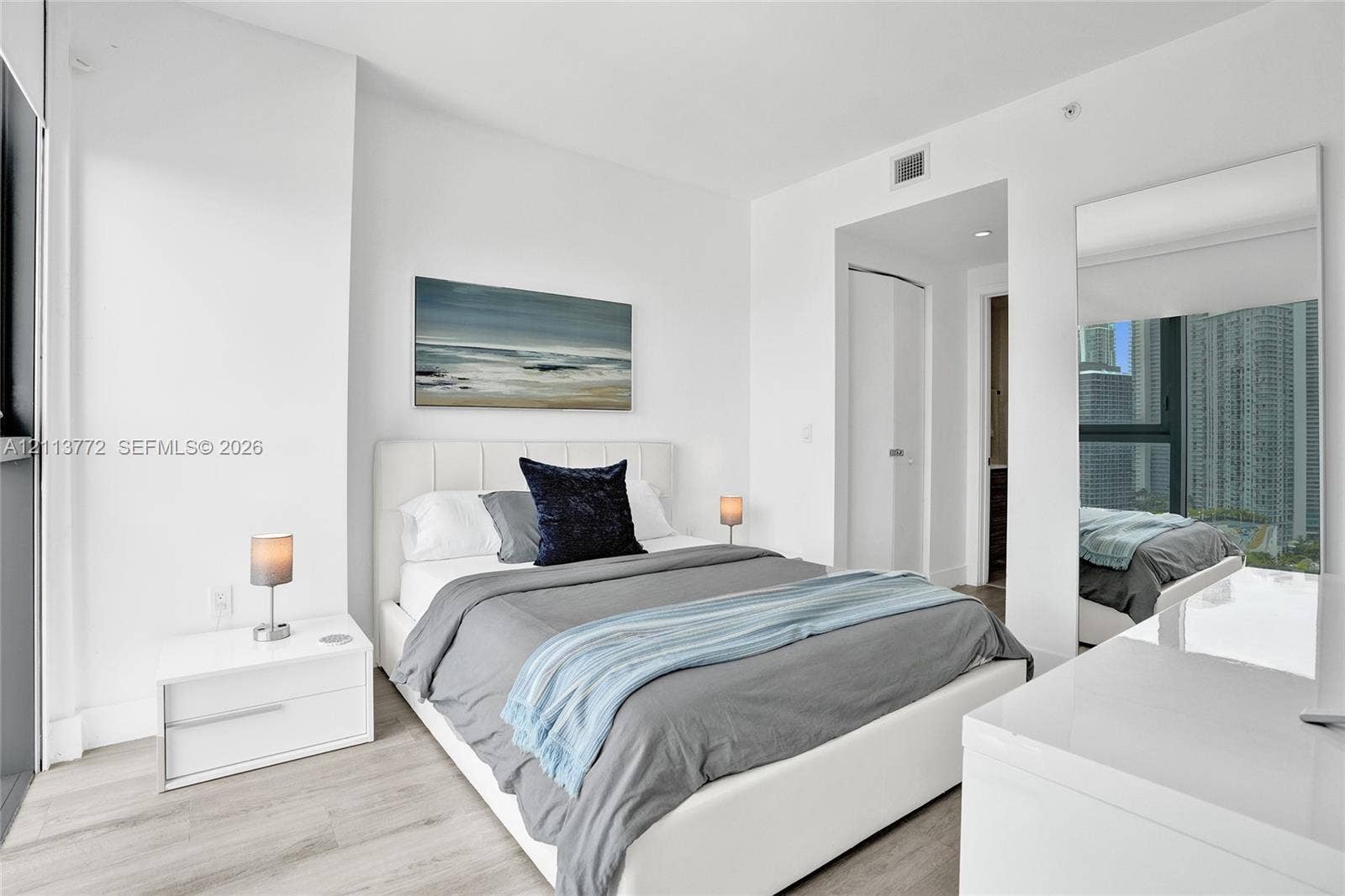 Neutral-toned wood-finish flooring, floor-to-ceiling window, and full-length wall mirror