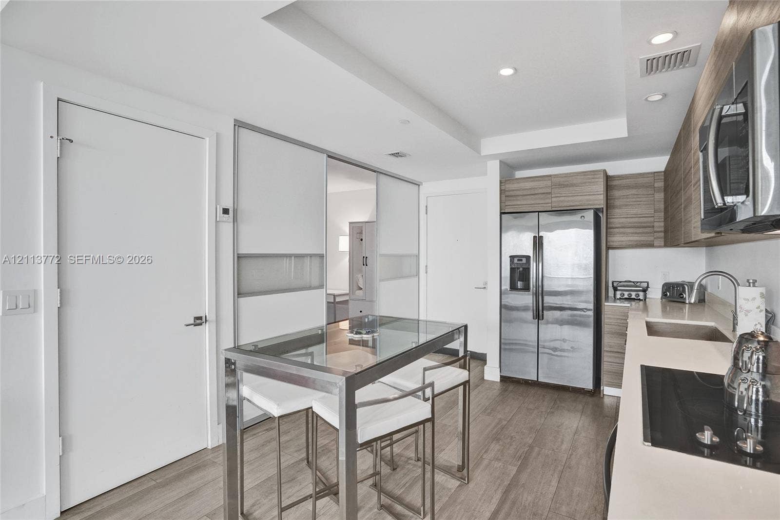 Kitchen featuring horizontal wood-grain cabinetry, stainless steel side-by-side refrigerator, recessed lighting, wood-finish flooring, and solid-surface countertops