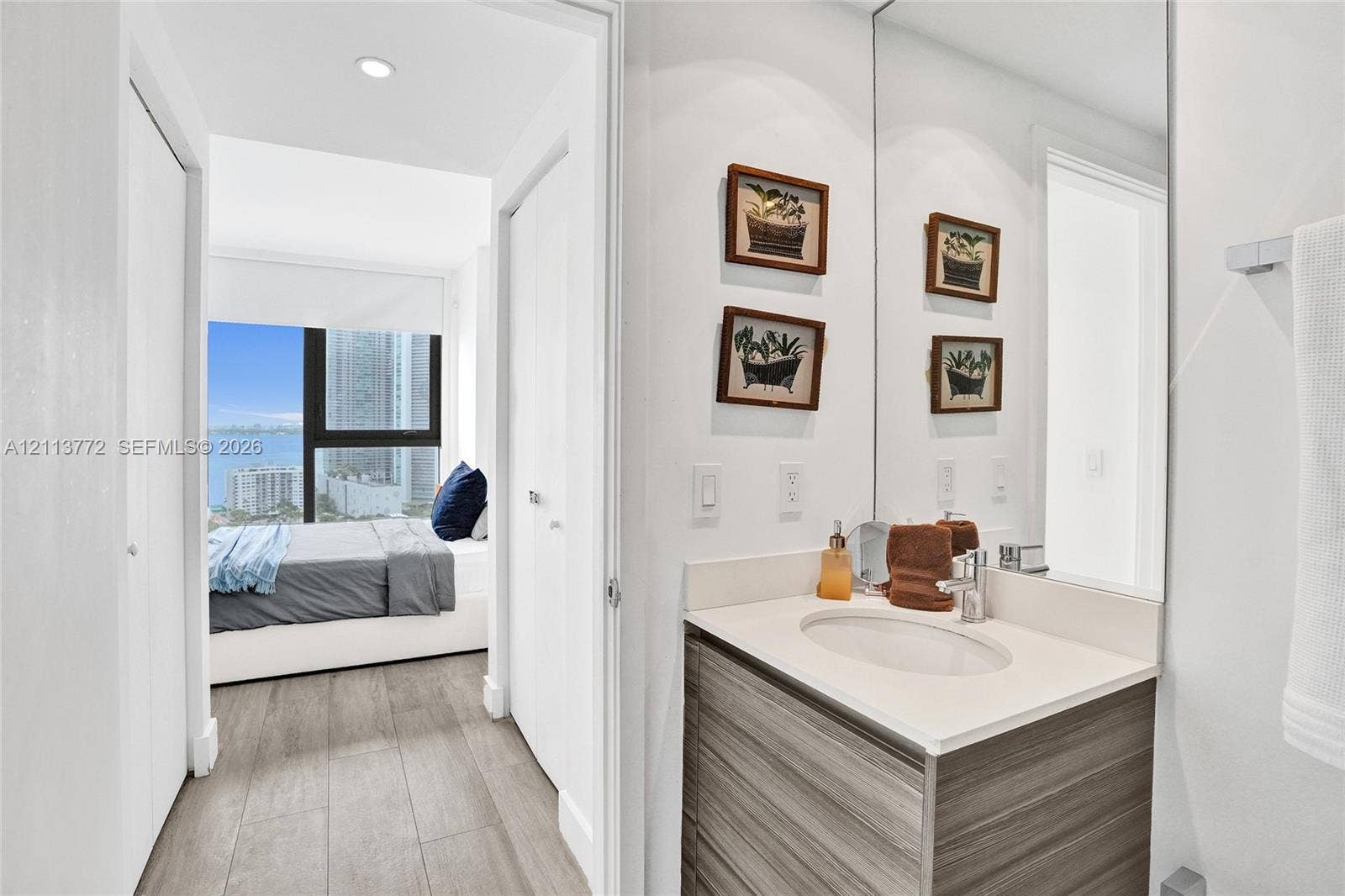 Bathroom featuring a vanity with wood-finish cabinetry, integrated countertop, oval undermount sink, and full-height wall mirror