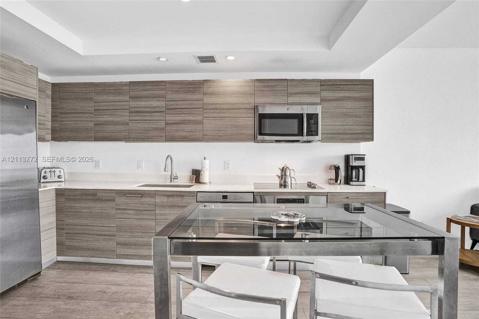 Kitchen featuring wood-finish cabinetry, stone-surface countertops, stainless steel appliances, recessed ceiling lighting, and wood-finish flooring