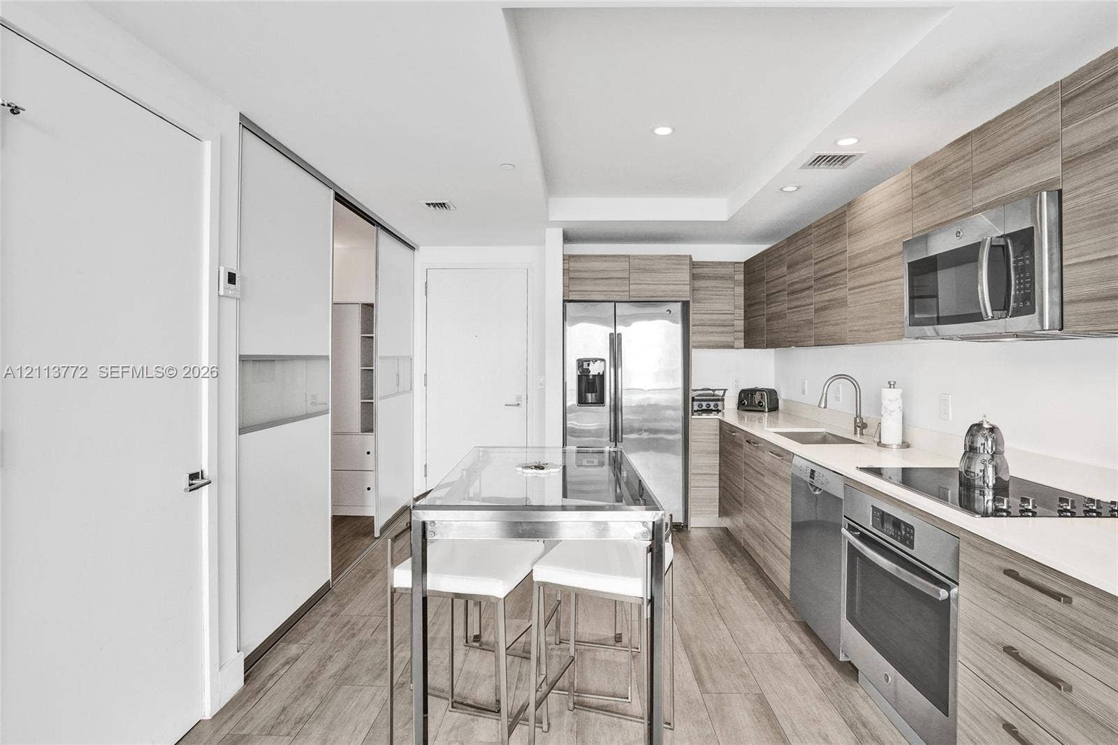 Kitchen featuring horizontal wood-grain cabinetry, stainless steel appliances, solid surface countertops, and wood-finish flooring