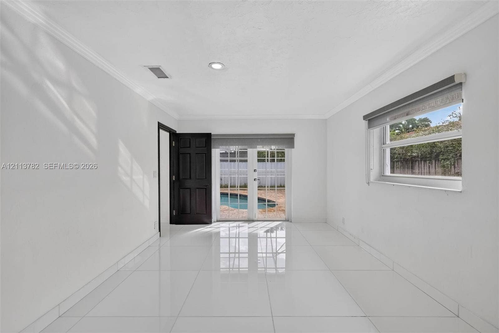 4720 Bayview Drive, Fort Lauderdale, FL 33308 Interior room featuring large-format tile flooring, recessed lighting, crown molding, and double glass-paneled exterior doors with roller shades