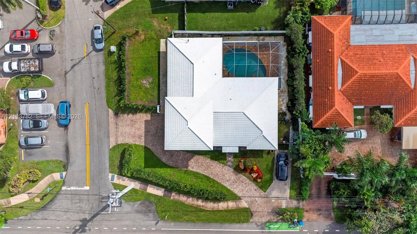 4720 Bayview Drive, Fort Lauderdale, FL 33308 Aerial perspective featuring a light-toned hip roof, paver driveway, and a screened-in pool enclosure