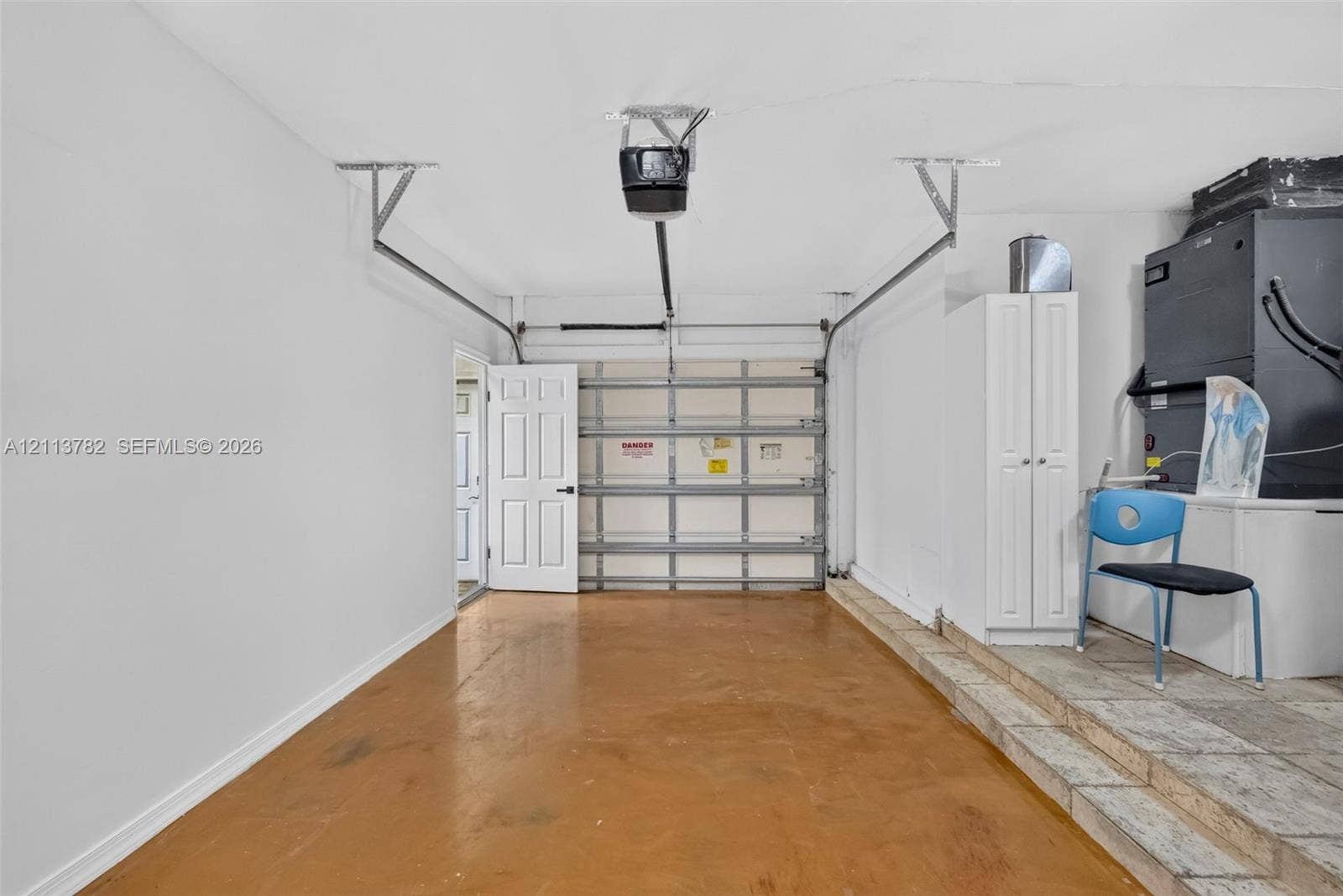 4720 Bayview Drive, Fort Lauderdale, FL 33308 Single-car garage featuring a roll-up door, automated door opener, built-in storage cabinetry, and concrete flooring