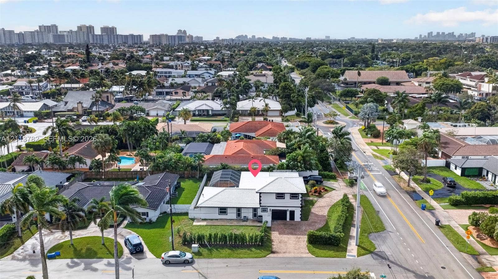 4720 Bayview Drive, Fort Lauderdale, FL 33308 Two-story residence featuring a paved circular driveway, white exterior finish, multi-pitched roofline, and a screened rear lanai