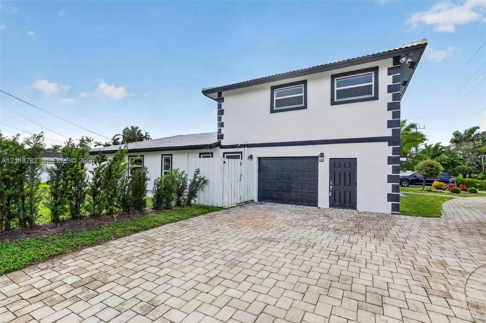 4720 Bayview Drive, Fort Lauderdale, FL 33308 Two-story exterior featuring a high-contrast facade, paver driveway, single-car garage, and perimeter landscaping