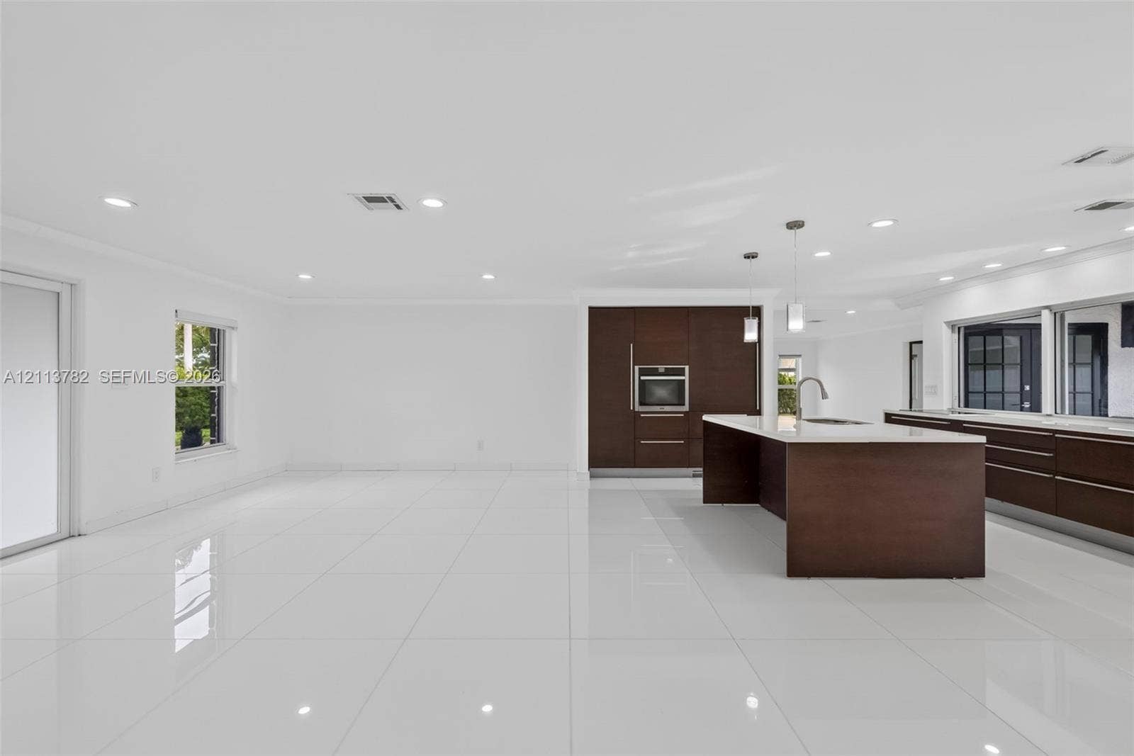 4720 Bayview Drive, Fort Lauderdale, FL 33308 Open-concept kitchen featuring dark wood-finish cabinetry, a large center island with stone-surface countertop, recessed lighting, and white tile flooring throughout
