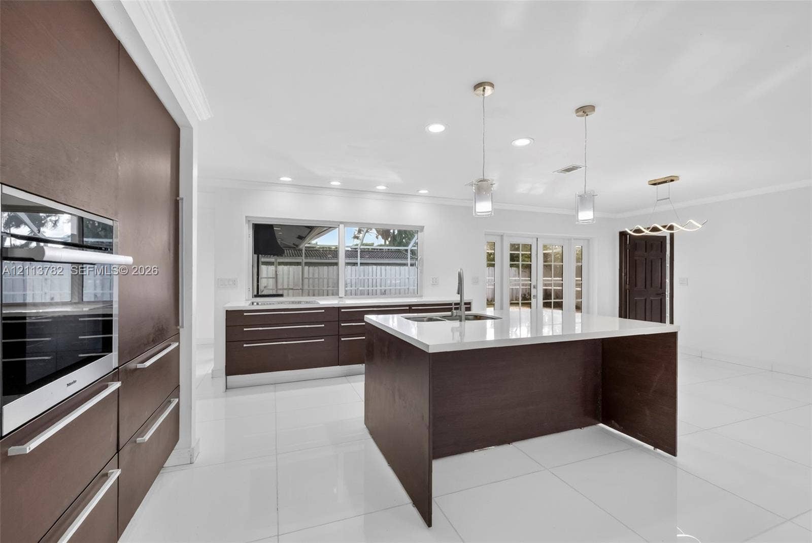 4720 Bayview Drive, Fort Lauderdale, FL 33308 Kitchen featuring flat-panel cabinetry, a central island with a solid-surface countertop, recessed ceiling lighting, pendant light fixtures, and polished tile flooring