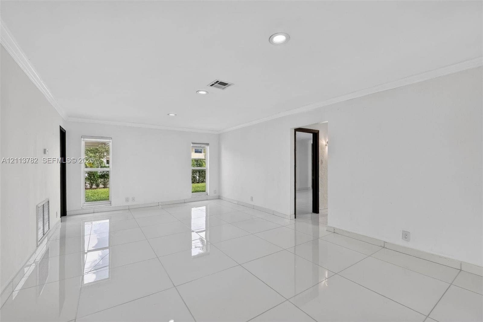 4720 Bayview Drive, Fort Lauderdale, FL 33308 Bright living area featuring large-format polished tile flooring, recessed lighting, crown molding, and dual windows