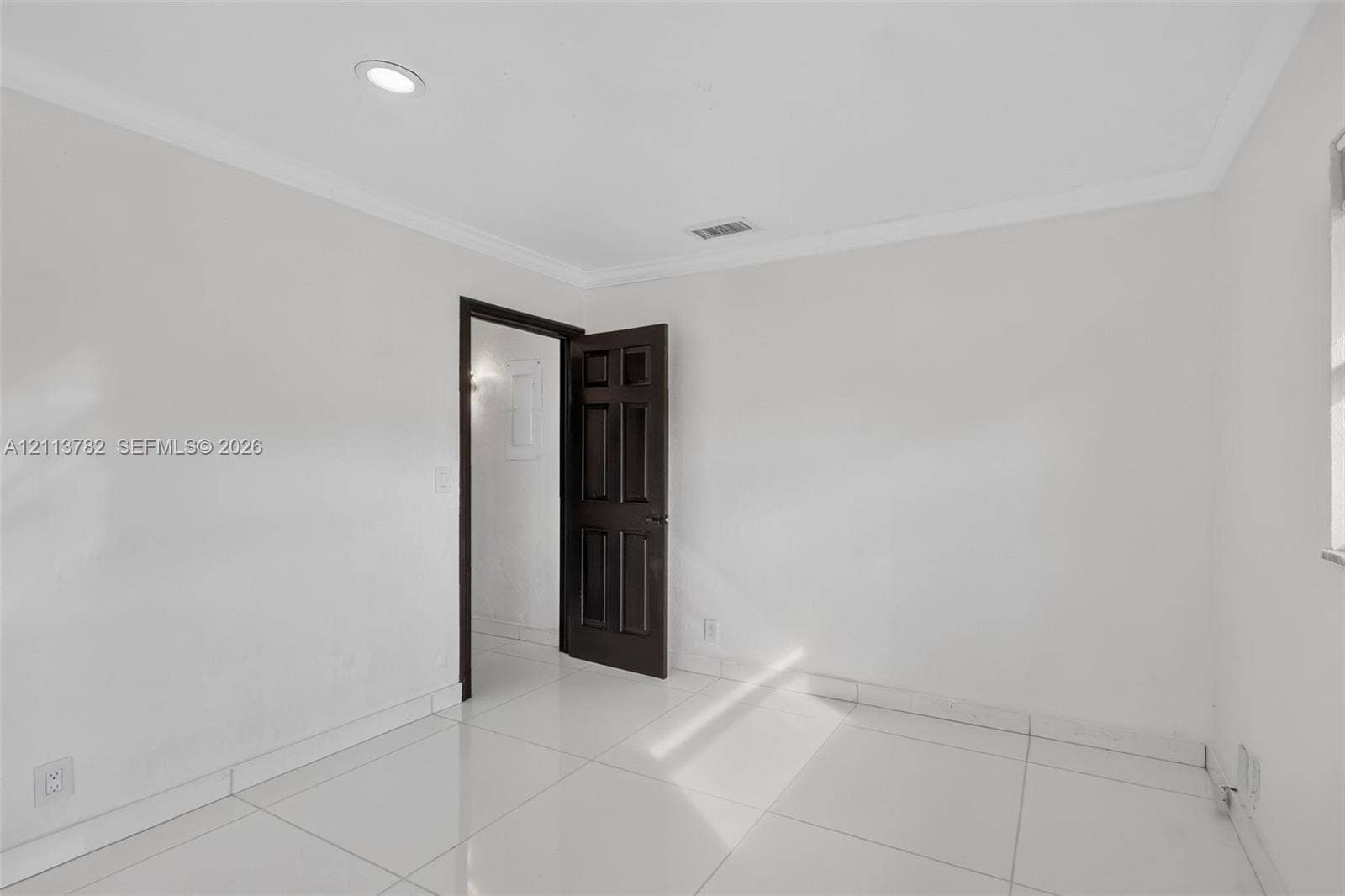 4720 Bayview Drive, Fort Lauderdale, FL 33308 Interior room featuring large-format tile flooring, crown molding, recessed lighting, and a six-panel dark wood-finish door