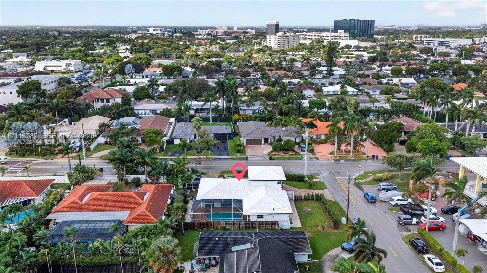 4720 Bayview Drive, Fort Lauderdale, FL 33308 Aerial perspective featuring a white-roofed residence with a screen-enclosed pool, perimeter fencing, and established palm trees in a residential neighborhood