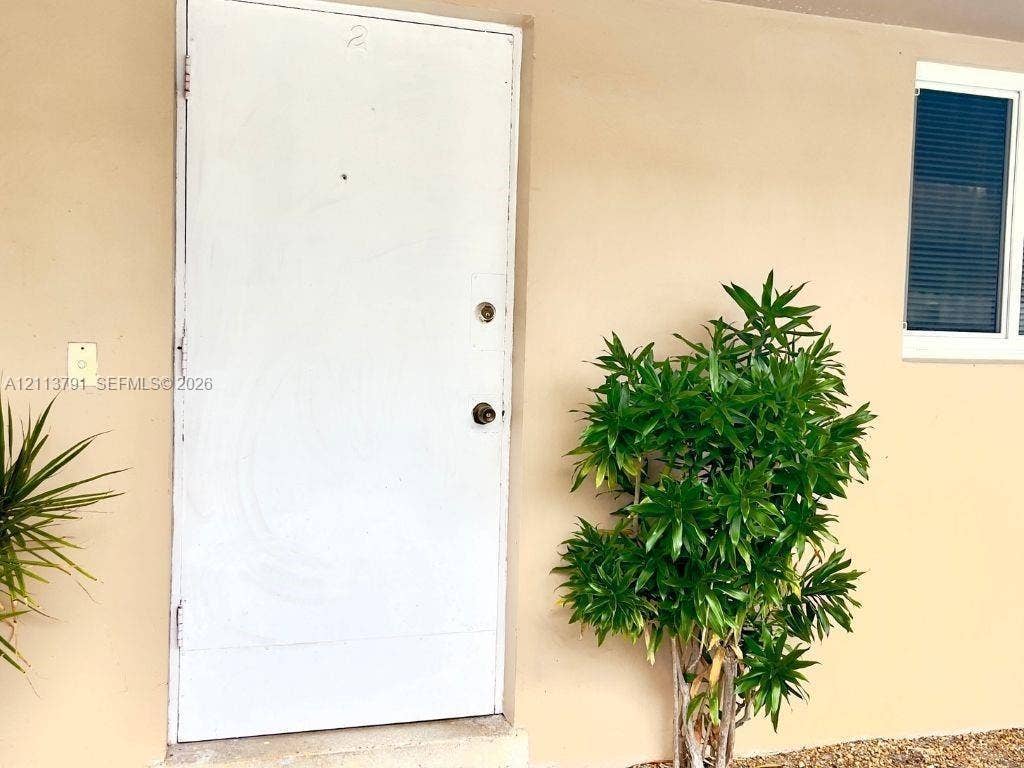 716 SE 18th Street, #1, Fort Lauderdale, Fort Lauderdale, FL 33316 Solid white entry door with a peephole and metallic hardware, flush-mounted wall lighting, and a window with horizontal blinds