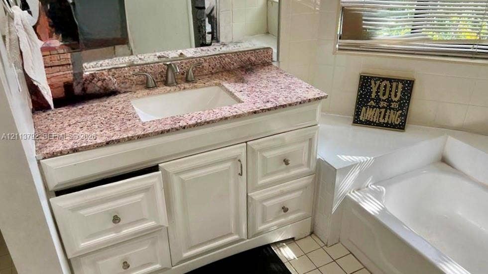 11530 NW 43rd, #1, Coral Springs, Coral Springs, FL 33065 Bathroom vanity featuring white cabinetry, a stone-composite countertop, and a recessed sink basin paired with a soaking tub and square floor tile