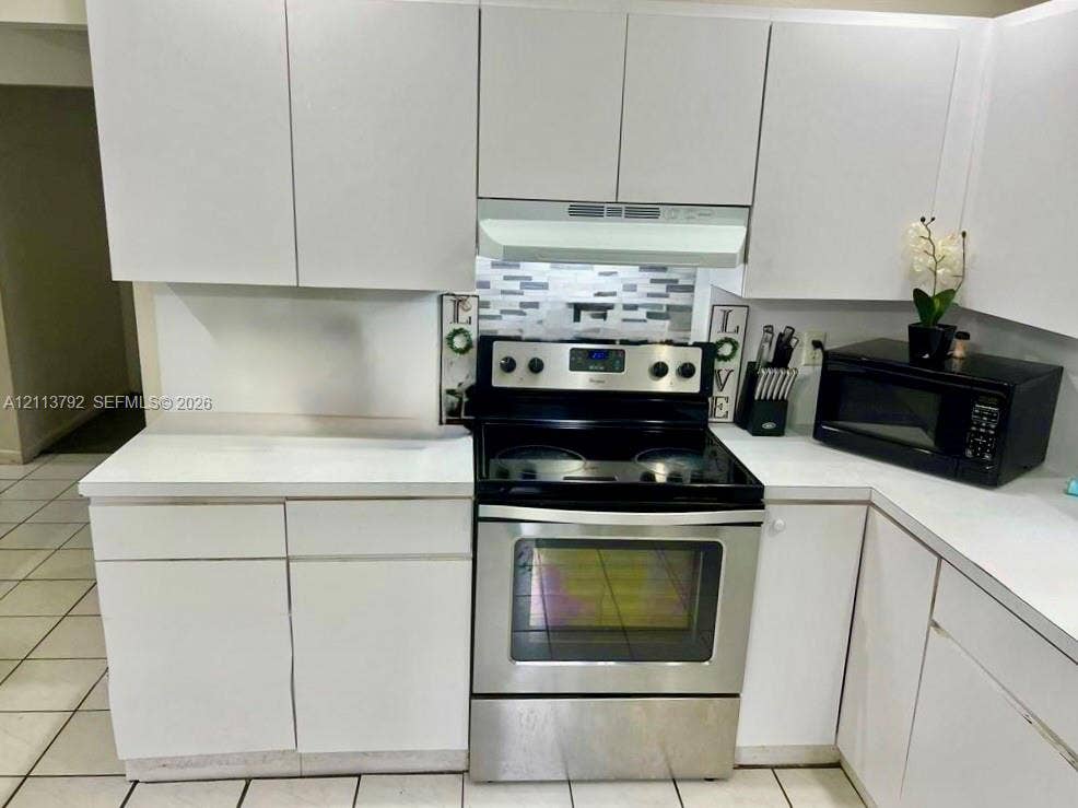 11530 NW 43rd, #1, Coral Springs, Coral Springs, FL 33065 Kitchen featuring white cabinetry, stainless steel range, matching over-the-range hood, mosaic tile backsplash, and light-toned floor tile