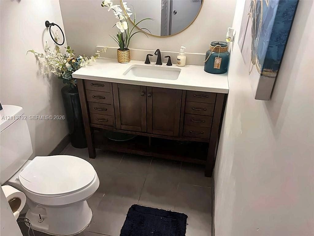 11530 NW 43rd, #1, Coral Springs, Coral Springs, FL 33065 Dark wood vanity with a white composite countertop, rectangular undermount sink, widespread oil-rubbed bronze faucet, circular gold-rimmed mirror, and tiled flooring