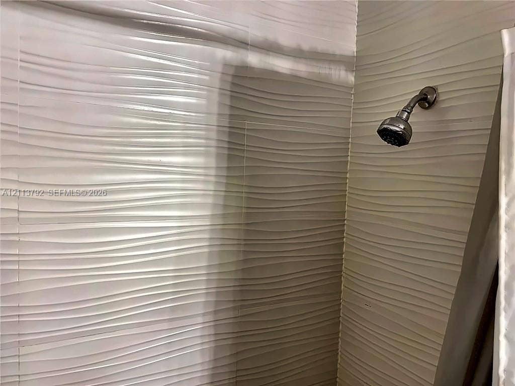 11530 NW 43rd, #1, Coral Springs, Coral Springs, FL 33065 Textured wall tiles featuring a horizontal wave pattern and a wall-mounted shower head with a metallic finish