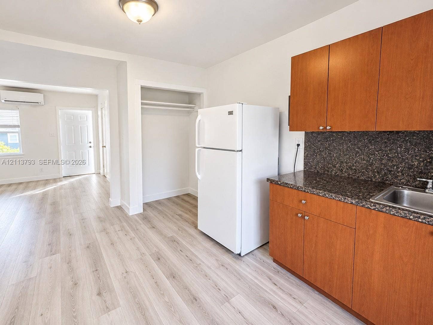 2638 Johnson Street, #53, Hollywood, Hollywood, FL 33020 Kitchenette featuring wood-finish cabinetry, stone-texture countertops, an integrated stainless steel sink, and wood-finish flooring