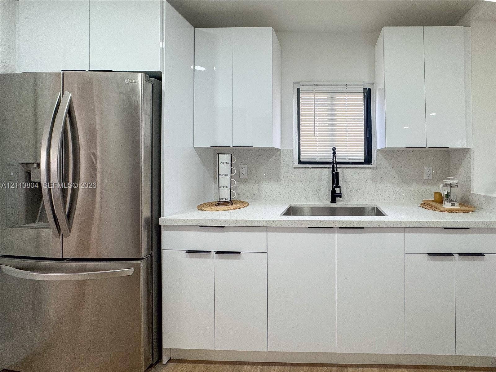 2300 NW 31st Avenue, Fort Lauderdale, FL 33311 Kitchen featuring white high-gloss cabinetry, stainless steel French door refrigerator, light-toned solid surface countertops, undermount sink, and matte black high-arch faucet