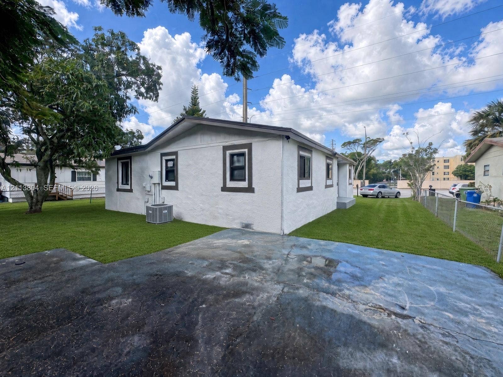 2300 NW 31st Avenue, Fort Lauderdale, FL 33311 Stucco exterior featuring dark-framed windows, a concrete parking area, and expansive lawn space
