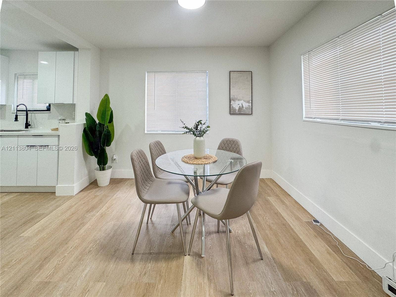 2300 NW 31st Avenue, Fort Lauderdale, FL 33311 Bright interior space featuring wood-finish flooring, white cabinetry, integrated matte black fixtures, and multiple windows with horizontal blinds